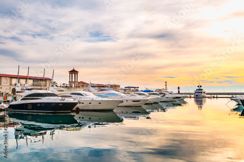 Luxury yachts at sunset. Marina of modern motor and sailing boats in sunshine. Reflection blue sky in water. Sea port dock. Travel and fashionable vacation. photo