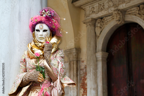 Carnival pink-gold-beige mask and costume at the traditional festival in Venice, Italy