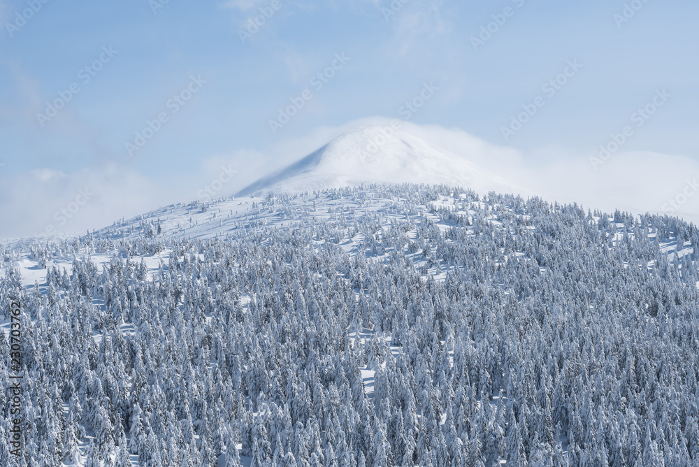 Winter landscape with mountain peak in the snow and clouds