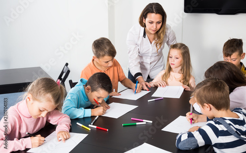 joyous little children with teacher drawing in classroom