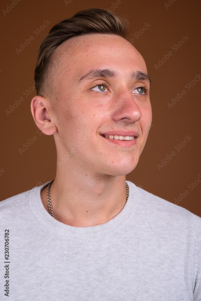 Young handsome man with blond hair smiling and thinking Young handsome man with blond hair smiling and thinking