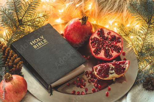 Fruits and vegetables for harvesting. Still life - bible and pomegranate on an iron plate in the branches of the Christmas tree