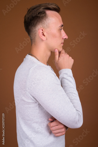 Young handsome man with blond hair against brown background