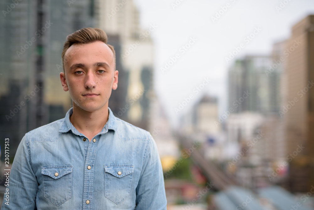Young handsome man with blond hair against view of the city Young handsome man with blond hair against view of the city