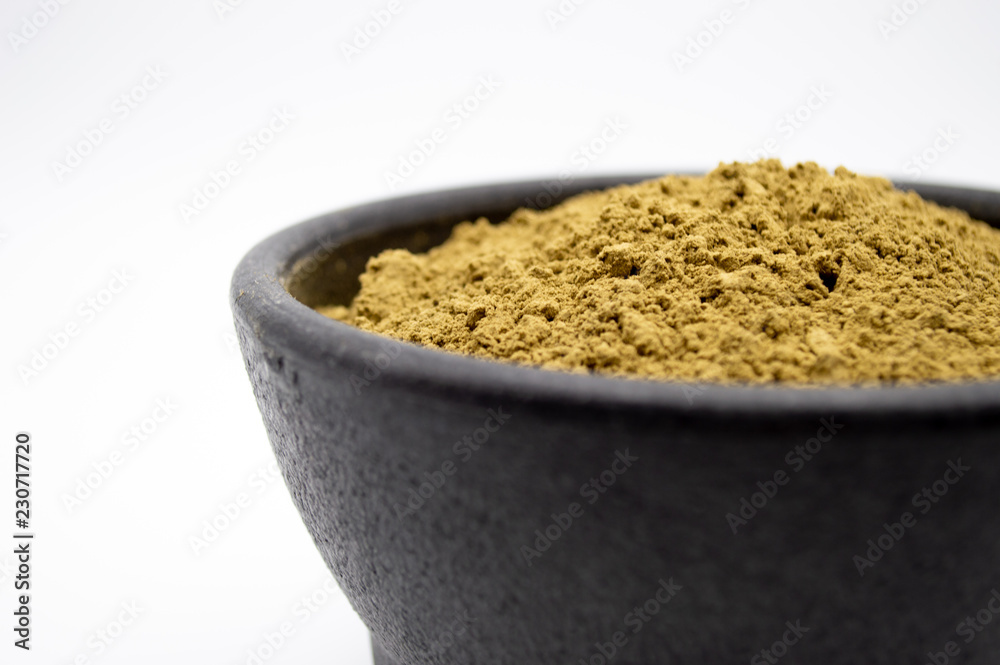 Maeng Da Kratom powder in black bowl isolated on a white background Maeng Da Kratom powder in black bowl isolated on a white background