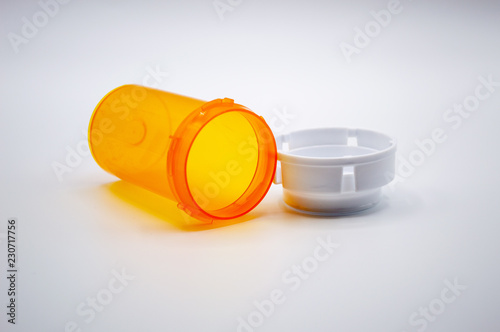 Empty orange medicine bottle with white cap on white background