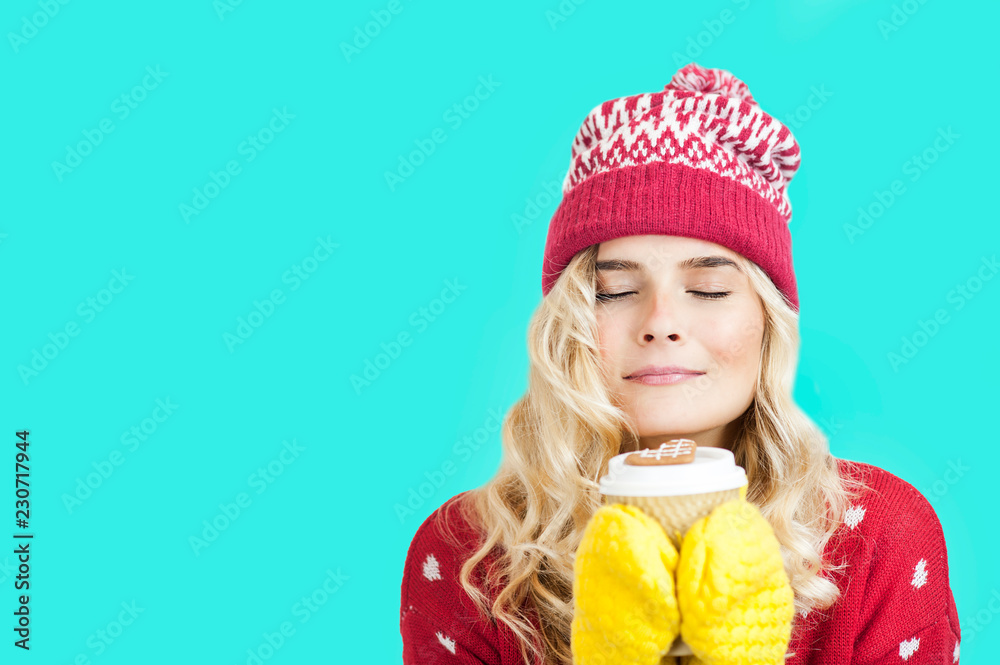 a very beautiful bright young girl of European appearance in a Christmas hat and sweater holding a cup of delicious coffee