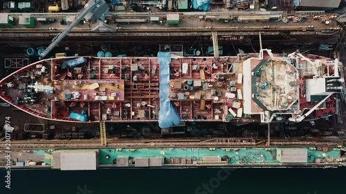 Drone flying above the cargo ship in the shipyard docks
