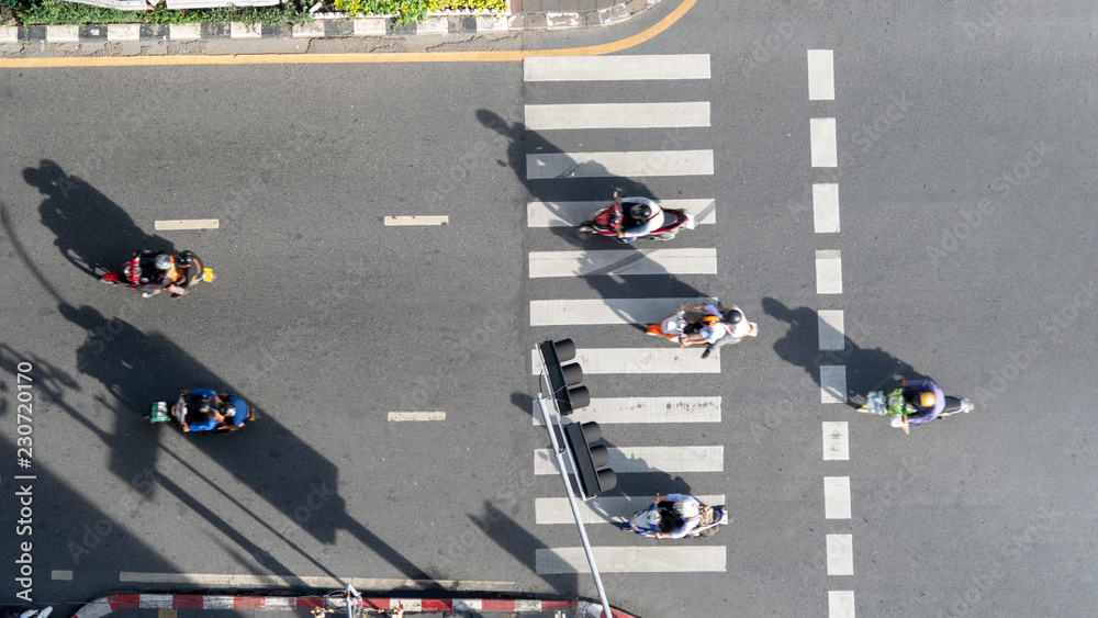 Fototapeta premium top aerial view of blur bikers ride the motorcycles to pass pedestrian crosswalk on road with the traffic pattern signage on the street
