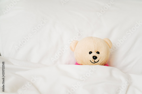 light brown smiling bear doll on bed in bead room