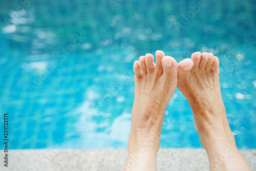 old woman feet, in soft focus, with blurred pool background and copy space