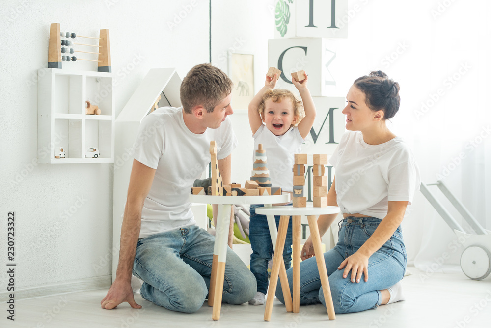 Fototapeta premium the family teaches the child how to play in a large bright room, concept development games, child development, study