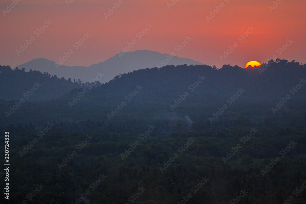 The background of the big sun, which is going to hide the mountains, and the light of the evening light, beautiful colors, beautiful nature of the season.