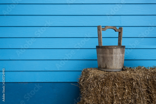 Countryside farm with blue wall and wooden bucket of water on the straw bale © Harnpon