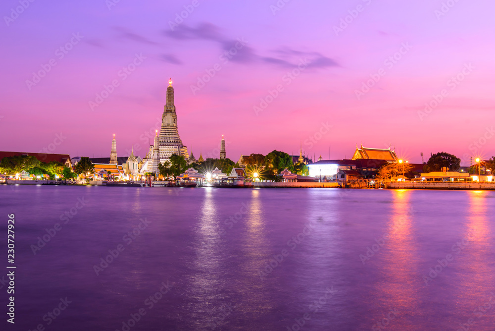 Fototapeta premium Wat Arun Ratchawararam Ratchawaramahawihan with reflections on the river in sunset time