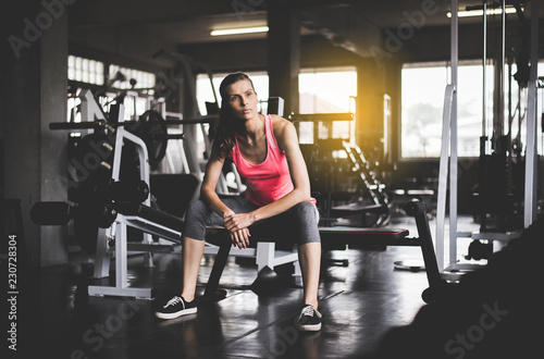 Fit woman sitting and relax after the training session in gym Concept healthy and lifestyle Female taking a break after exercise and workout