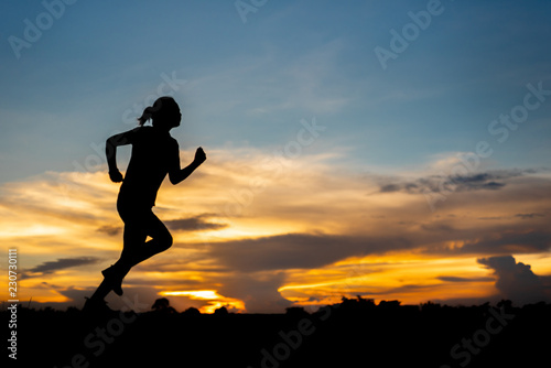 silhouette woman running alone at beautiful sunset in the park. © stcom