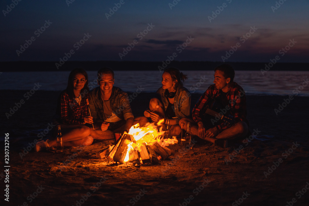 Camp on the beach. Group of young friends having picnic with bonfire Camp on the beach. Group of young friends having picnic with bonfire