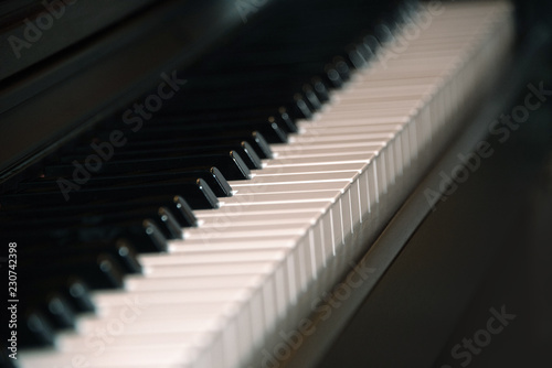 Closeup of black and white piano keys on a dark background.