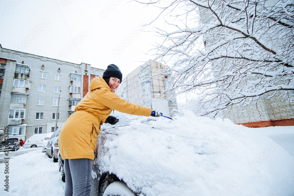 woman cleaning her car of snow after snowstorm