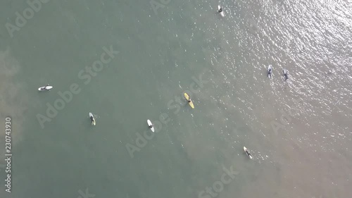 Drone Shot from behind of surfer riding a wave to shore through other surfers in Bolinas, CA photo