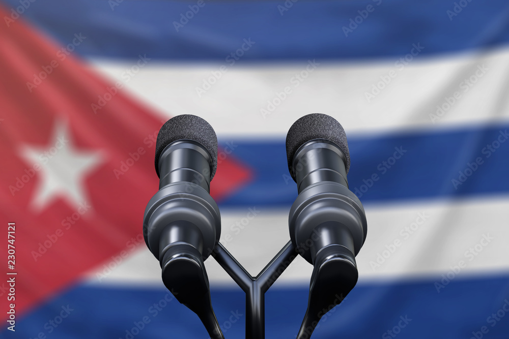 Podium lectern with two microphones and Cuba flag in background