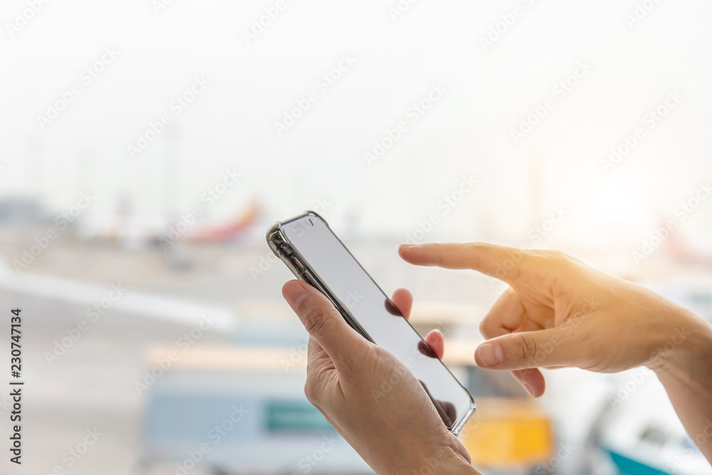 Close up of young woman hand using mobile smartphone in the terminal blurry background.