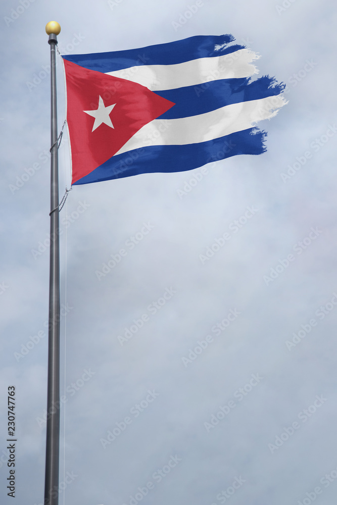 Worn and tattered Cuba flag blowing in the wind on a cloudy day