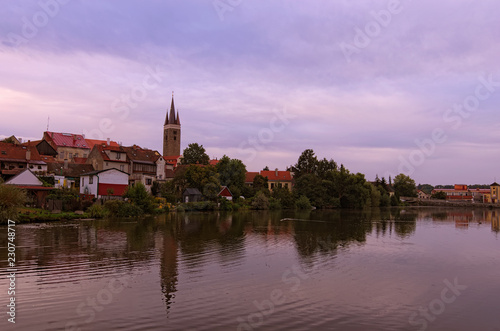 Morning cityscape of medieval Telc. Tower of Church of the Holy Spirit in Telc reflected in the water of the castle lake. A UNESCO World Heritage Site © evgenij84