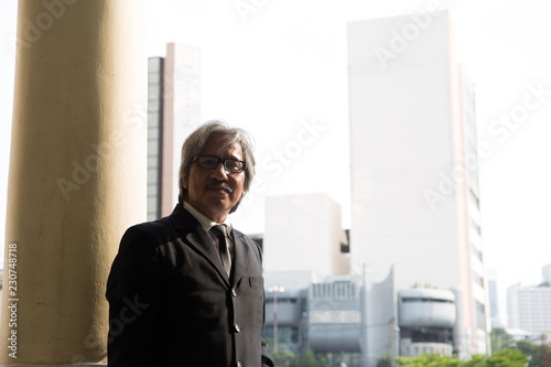 Asian business man in black suit and necktie stand against the pillar at Hua Lampong station, Bangkok, Thailand