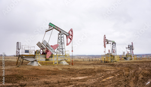 The oil pump, industrial equipment. Oil field site, oil pumps are running. Rocking machines for oil production