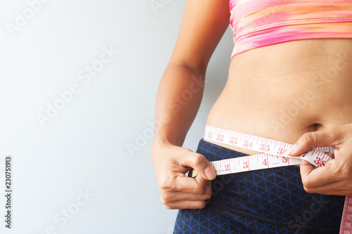 Sporty girl measuring her waist, Reducing excess weight