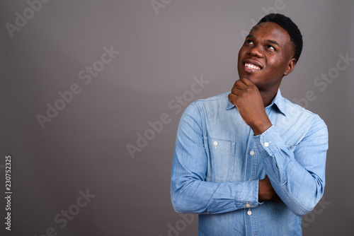 Young African man wearing denim shirt against gray background