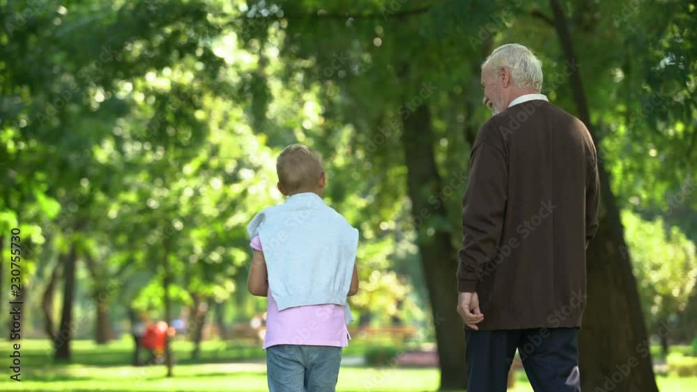 Granddad and grandson walking in park, discussing mens issues, sharing secrets Granddad and grandson walking in park, discussing mens issues, sharing secrets
