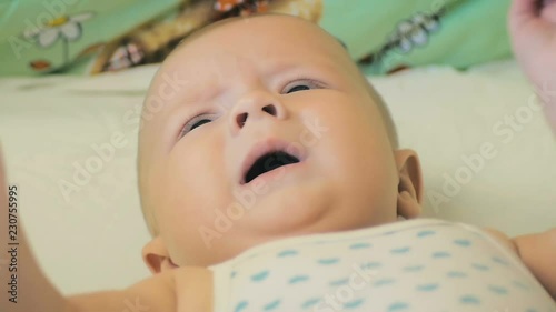 Close-up of a five-month-old baby lying in his children bed in slow motion.