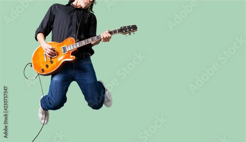 Male Guitarist playing music on grey wall
