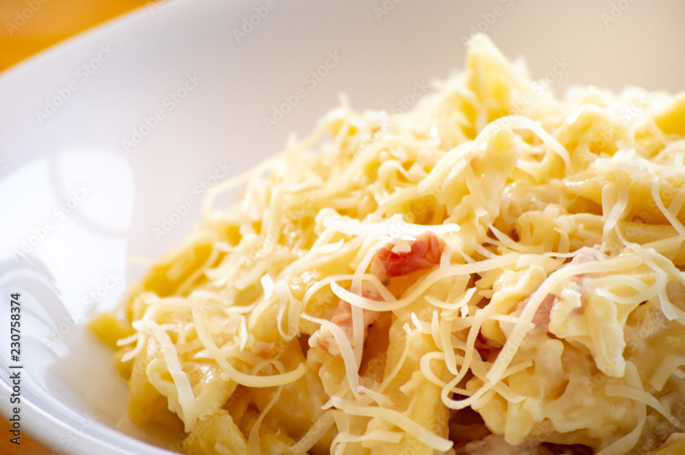 Macaroni carbonara on a white dish and orange background Macaroni carbonara on a white dish and orange background