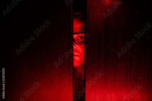 Agoraphobia concept / eye peeking behind the door photo