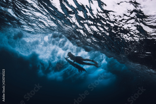 Canvas Print Surfer man with surfboard dive underwater