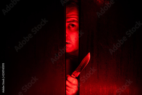 Serial killer / eye peeking behind the door with kinfe photo