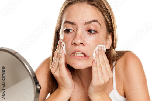 young beautiful girl cleaning her face with cotton pads on white backgeound