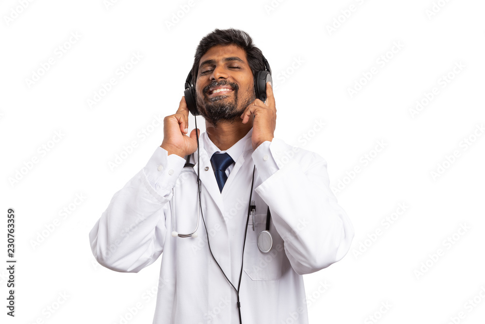 Indian doctor enjoying music while touching headphones. Indian doctor enjoying music while touching headphones.