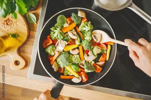 Man cooking fresh vegetables on pan