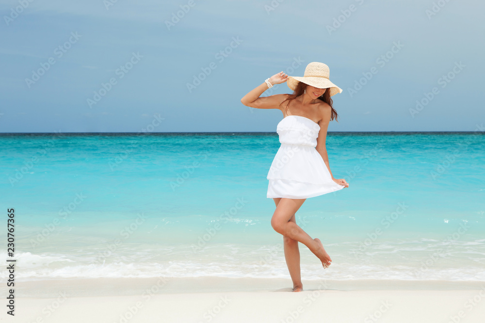 Fashion woman dancing on the beach. Happy island lifestyle. White sand, blue cloudy sky and crystal sea of tropical beach. Vacation at Paradise. Ocean beach relax, travel to Maldives islands Fashion woman dancing on the beach. Happy island lifestyle. White sand, blue cloudy sky and crystal sea of tropical beach. Vacation at Paradise. Ocean beach relax, travel to Maldives islands