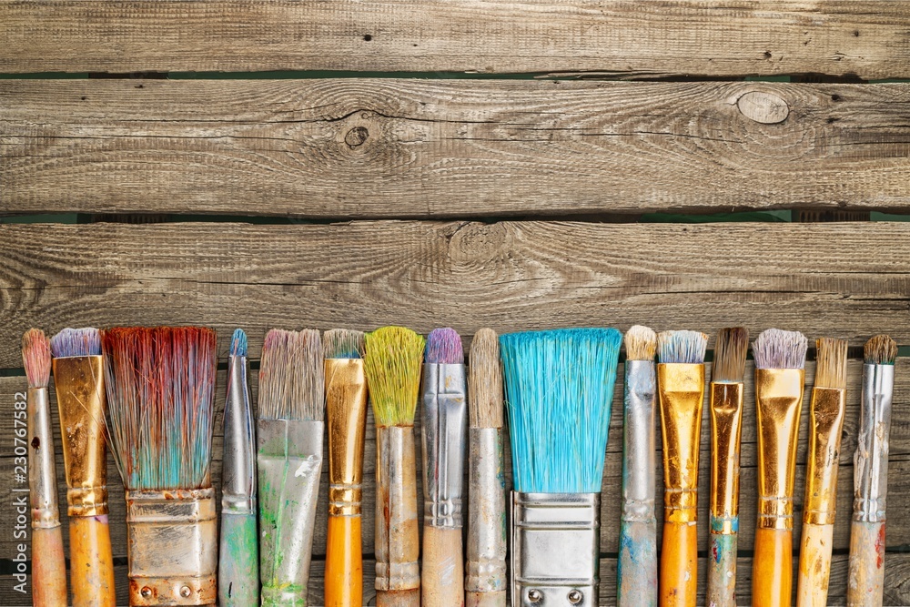 Row of artist paint brushes on desk - obrazy, fototapety, plakaty 