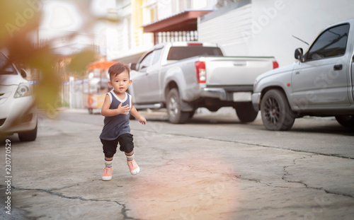The cute little boy is running in the morning. On the concrete road