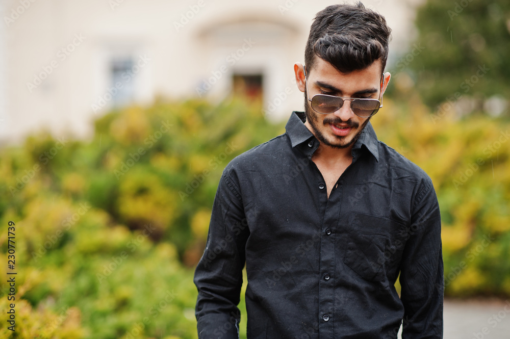 Indian stylish man at black shirt and sunglasses posed outdoor. Indian stylish man at black shirt and sunglasses posed outdoor.