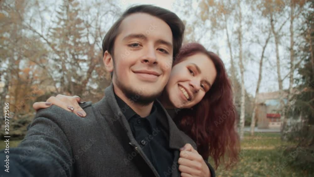 Couple of loving young people is taking photo themselves in the autumn park. Couple of loving young people is taking photo themselves in the autumn park.