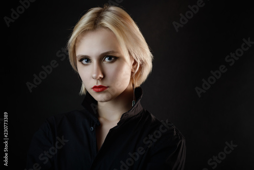 Portrait of a young woman with blue eyes in black shirt.