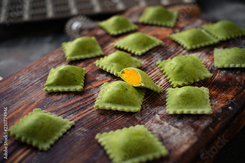 uncooked green organic ravioli pasta with pumpkin topping handmade on kitchen table